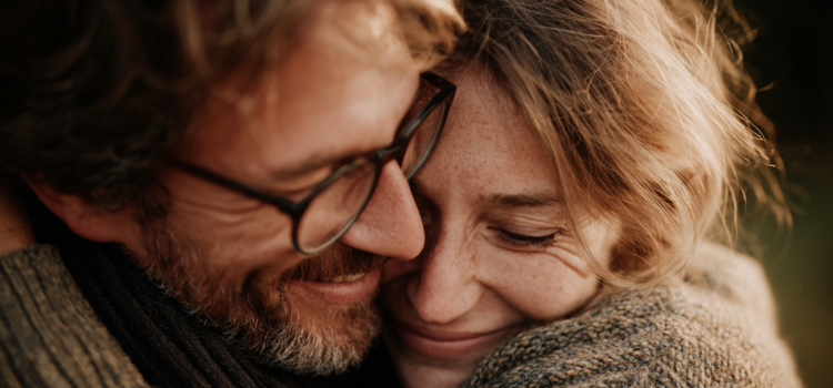 What Happens When You Fall in Love? (+ How Love Evolves) Ein Mann und eine Frau umarmen sich und lächeln, weil sie verliebt sind.