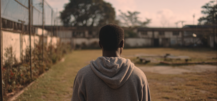 A young man from behind wearing a gray sweater standing outside