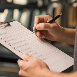 A man holding a checklist in a gym illustrates the importance of applying discipline