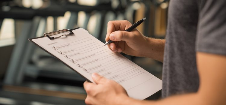 A man holding a checklist in a gym illustrates the importance of applying discipline