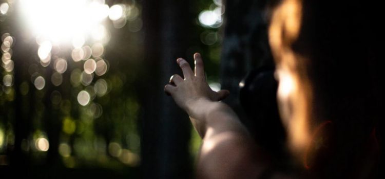 How to Overcome Learned Helplessness With Optimism girl reaching towards the sunlight
