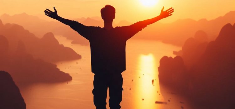 A silhouette of a man displaying emotional discipline as he stretches out his arms against a scenic river.