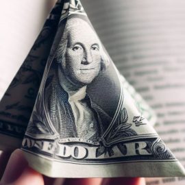 A dollar shaped as a triangle in front of an open book.
