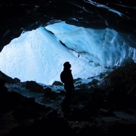 A silhouette of person underground in an ice cave.