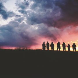 A silhouette of a group of people at a sunset.