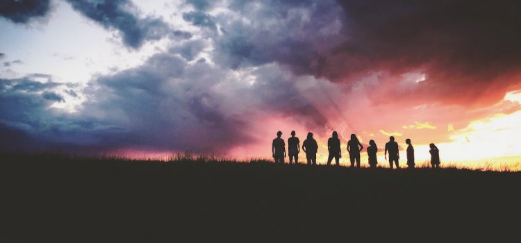 A silhouette of a group of people at a sunset.