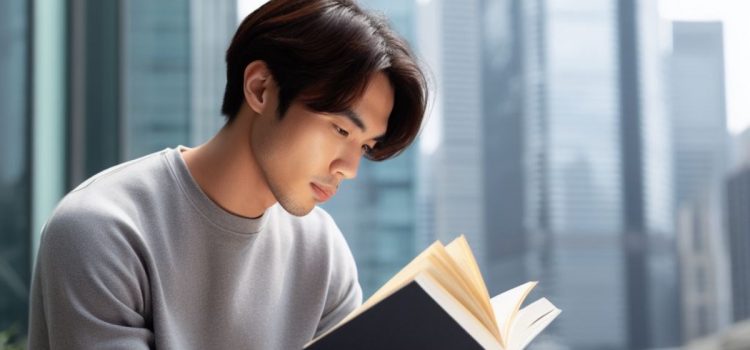 A young man reading a book with a view of a city.