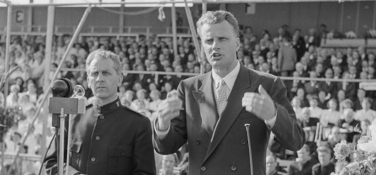 Billy Graham preaching to a crowd.