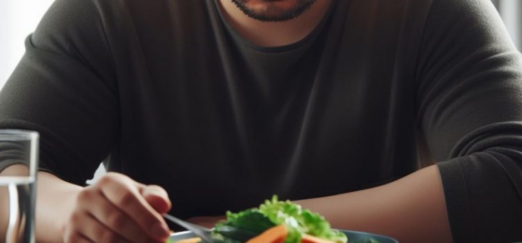 A man intermitting fasting while looking at a plate of veggies and water.