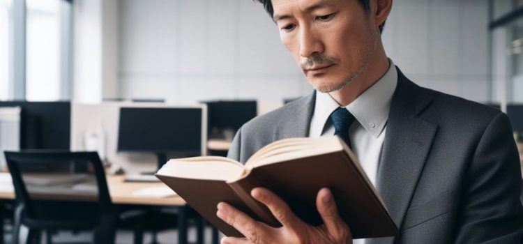 A professional man in suit and tie reading a book in an office