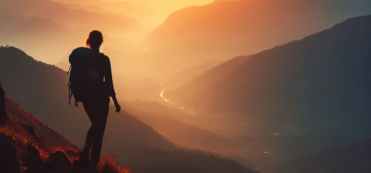 A hiker learning how to be present in the moment as they look out at a mountain scenery.