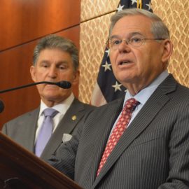 Senator Robert Menendez speaking at a press conference in front of a microphone.