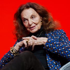 Fashion designer Diane von Fürstenberg sitting against a red background.