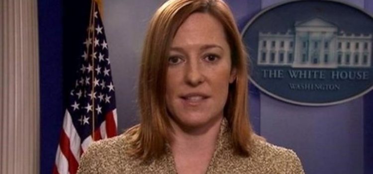 Jen Psaki in the White House briefing room in front of an American flag.