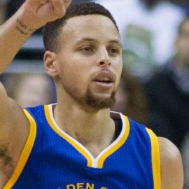 Stephen Curry raising his arm in a basketball game.