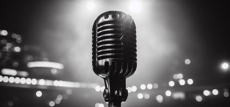 A black and white image of stage lights behind a microphone used for beginner stand-ups.