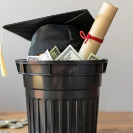 A college degree and graduation cap in the trash as some wonder, "is going to college worth it?"