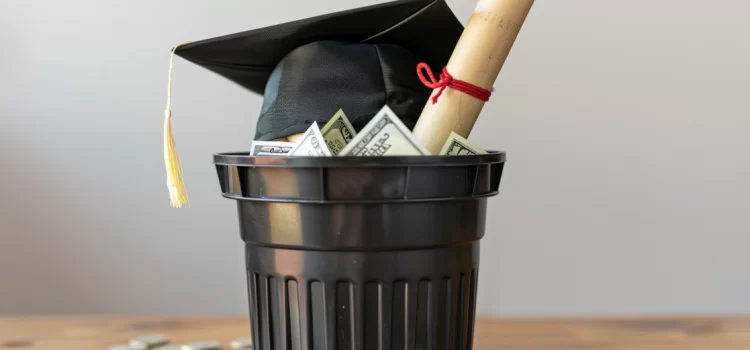 A college degree and graduation cap in the trash as some wonder, "is going to college worth it?"