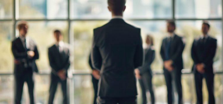 What Is a Functional Manager? The Responsibilities & Skills A functional manager standing in front of a team of employees near a glass window.