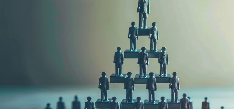 Say Goodbye to the Workplace Hierarchy With These 2 Steps Mini figurines in business suits standing in a pyramid, representing a workplace hierarchy.