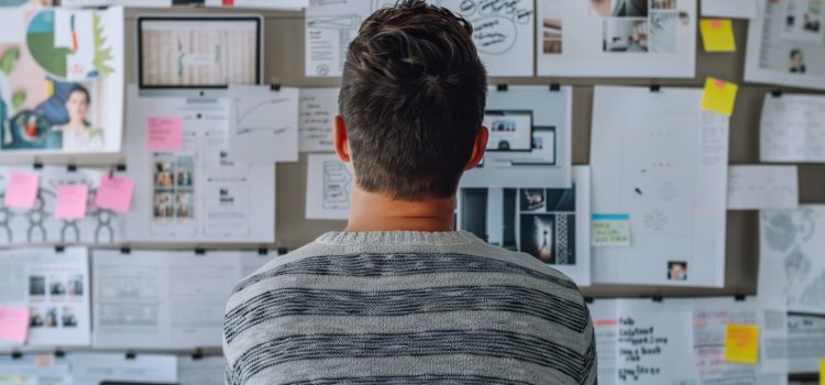 How Outcome-Based Planning Guarantees Great Results A man looking at a wall of papers and notes using outcome-based planning.