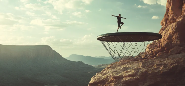 3 Causes of Human Error: How Heuristics Lead Us Astray a man jumping on a trampoline on a mountain cliff illustrates the causes of human error