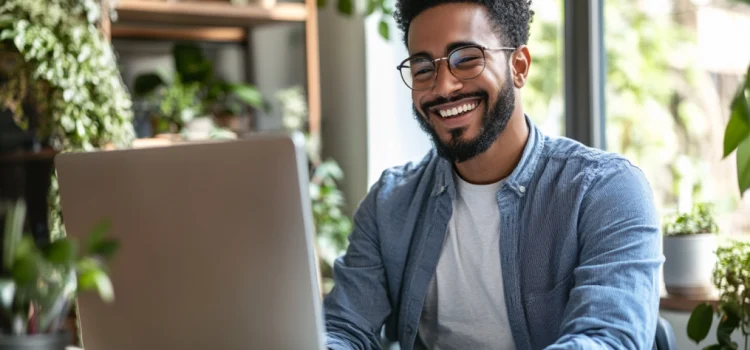 Online Content Creation: 3 Tips for Crafting Engaging Pieces a smiling bearded man with eyeglasses engaging in online content creation at a computer in a room with lots of plants