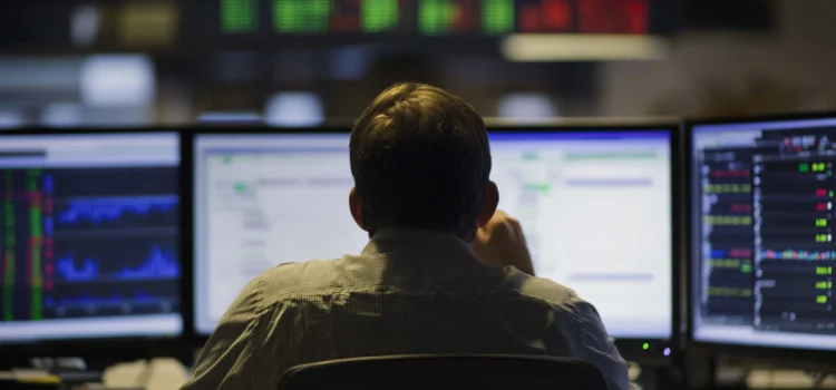Risk Tolerance vs. Risk Aversion: How Emotions Run the Market A man looking at stocks on computer screens, deciding between Risk tolerance vs risk aversion