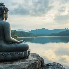 A statue of a buddhist practicing mindfulness meditation in front of a lake