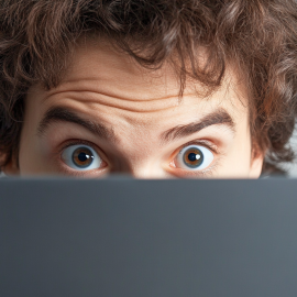 A man with a surprised expression behind a laptop illustrates AI manipulation