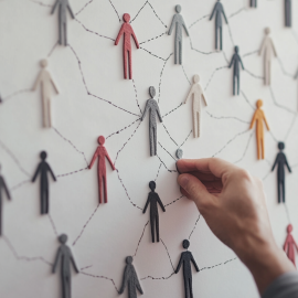 A man's hand connecting people-shaped figures on a whiteboard illustrates social unity