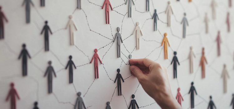 A man's hand connecting people-shaped figures on a whiteboard illustrates social unity