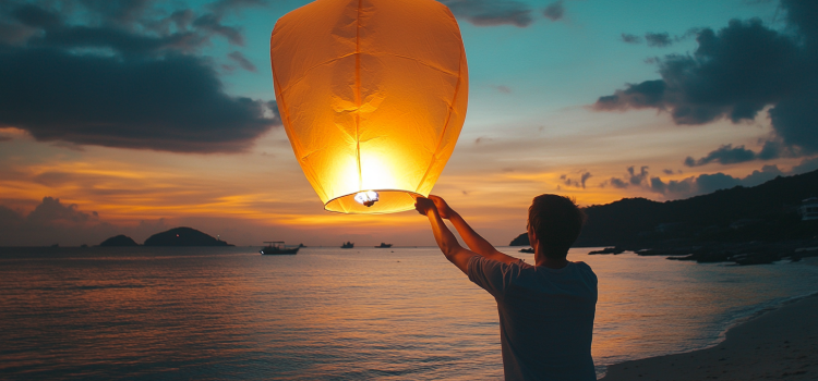 A man letting go of a paper lantern on a beach, representing the Let Them Theory