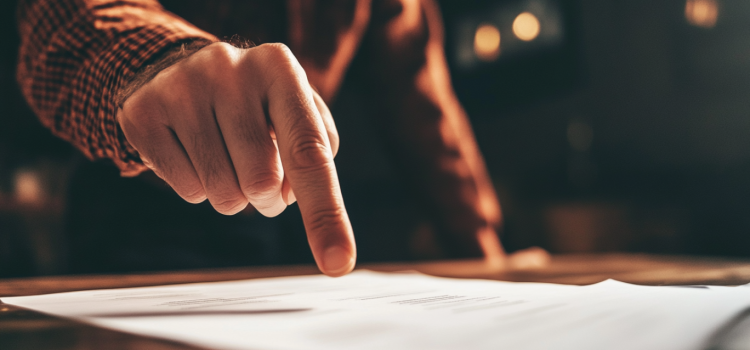 A man's finger pointing at a document on a desk, portraying the importance of writing with purpose
