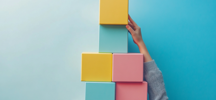 A hand holding up a structure of colored blocks on a plain background