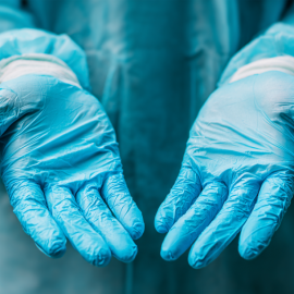 An up-close shot of a surgeon wearing a gown and gloves