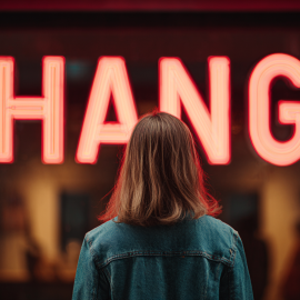 A woman looking at a neon sign that reads "CHANGE"