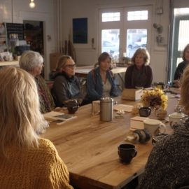 A book club made up of several women sitting around a table in a book store discussing a book