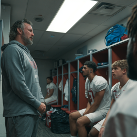A coach talking to football players in the locker room