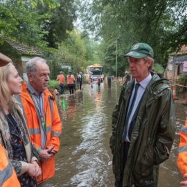 Government officials and disaster relief personnel talking at the site of a flood