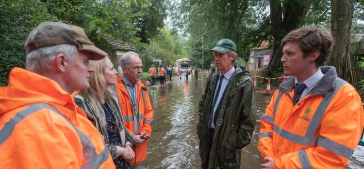 Government officials and disaster relief personnel talking at the site of a flood