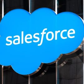 A Salesforce sign hanging on a building with glass windows