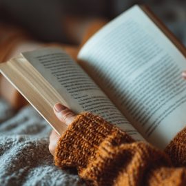 A woman holding a book and reading in bed