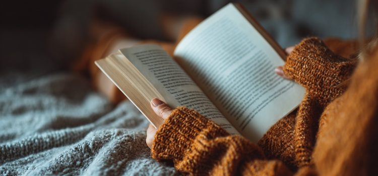 A woman holding a book and reading in bed