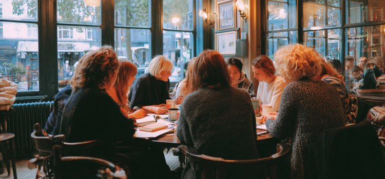 Sapiens Discussion Questions, Sample Answers, & Activities Ten women in a book club discussion sitting around a table in a restaurant