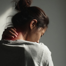 A woman holding the back of her neck because she's suffering from chronic pain