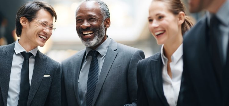 Compañeros de trabajo (tres hombres y una mujer) sonriendo y riendo juntos.