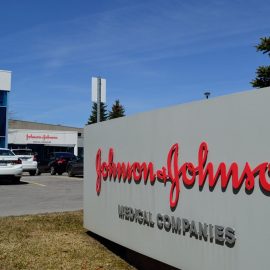 A sign that reads "Johnson & Johnson" in red letters in front of an office building