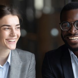 Uma mulher e um homem sorridentes em trajes profissionais