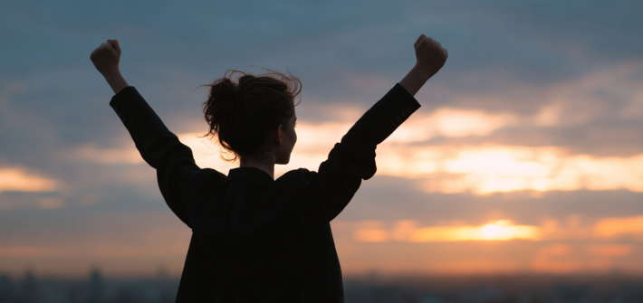 A successful woman holding her arms up in the air